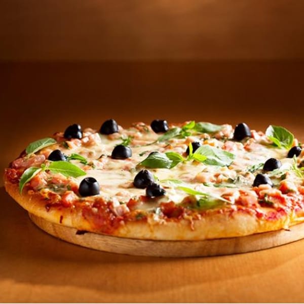 A Paramount Pizza 3 pizza with olives, basil, and melted cheese on a wooden board.